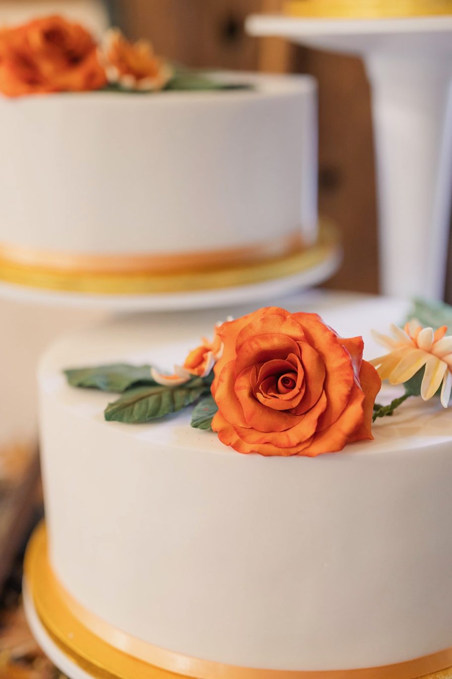 Wedding cake tier topped with finely made orange sugar flower rose Wedding cake tier topped with finely made orange sugar flower rose